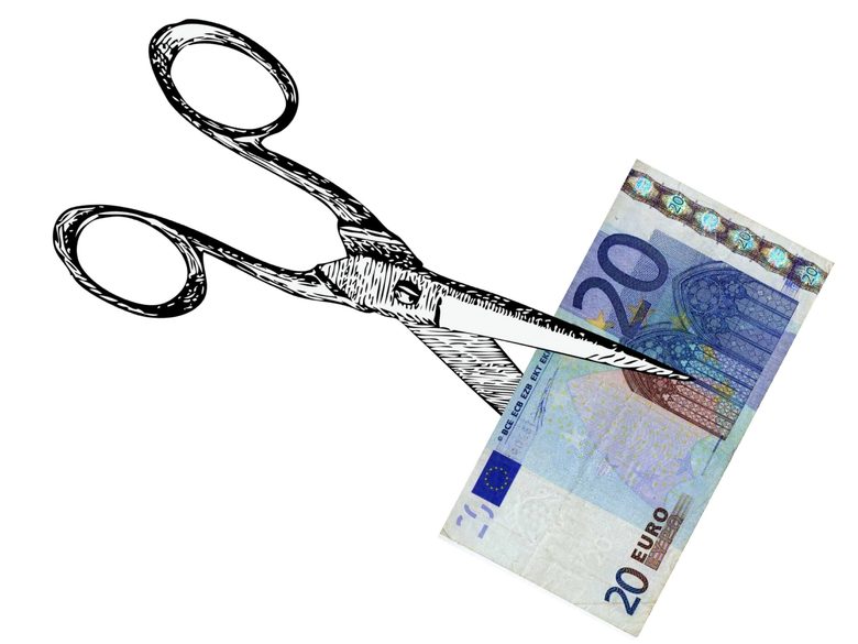 Kuvassa piirretyt terässakset leikkaavat 20 euron seteliä.